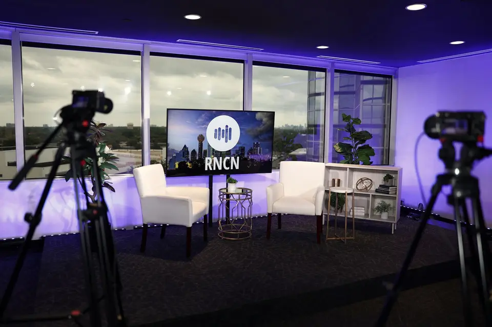 Talk Show Studio in Dallas with white guest chairs, production cameras, and RNCN backdrop
